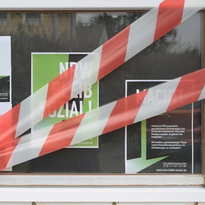 Auf dem Fenster einer Kita kleben Protestplakate und rot-weißes Absperrband.