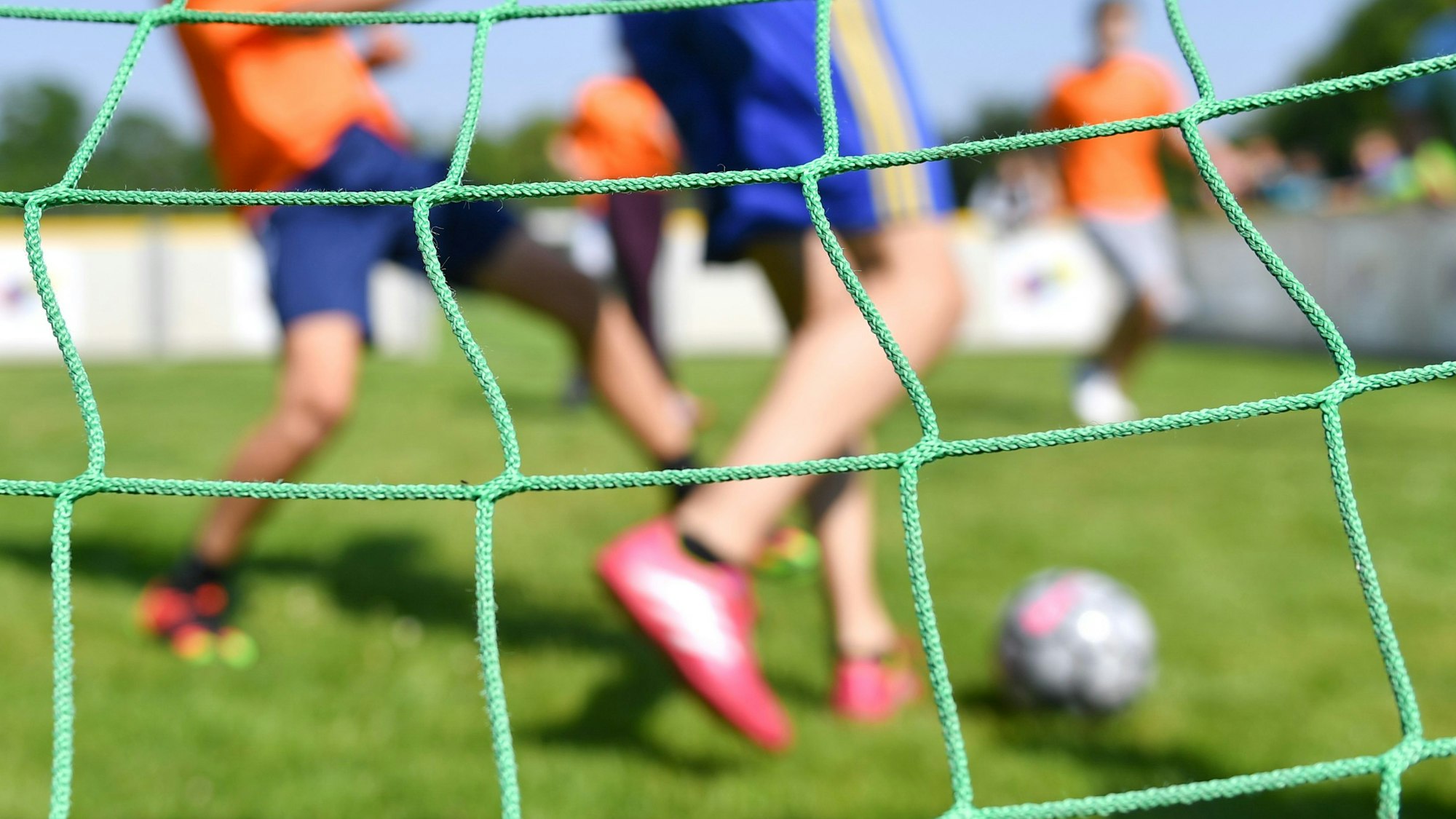 Kinder spielen auf einem Sportplatz Fußball.