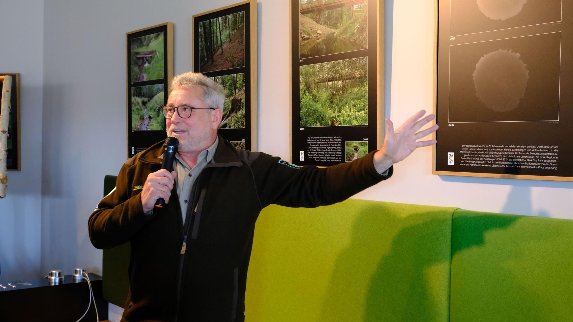 Michael Lammertz deutet auf die Bilder der Ausstellung im Nationalpark-Zentrum.