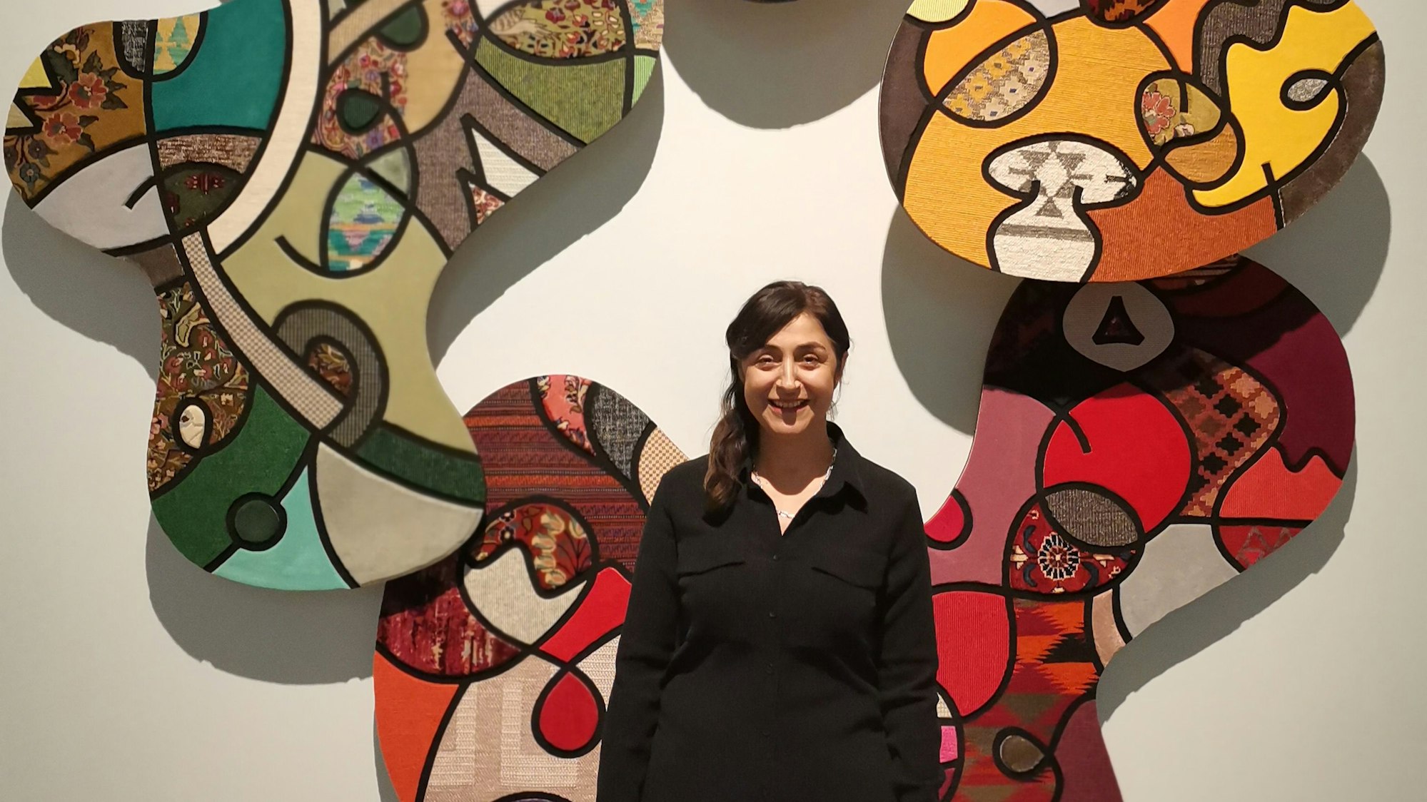 Auf dem Bild ist eine Künstlerin mit ihrer Wandarbeit zu sehen.