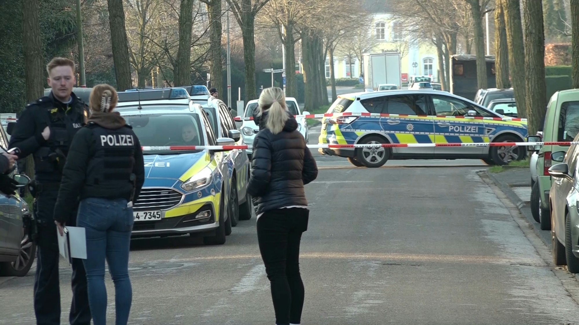Ochtrup: Einsatzkräfte der Polizei stehen vor Absperrband auf einer Straße.