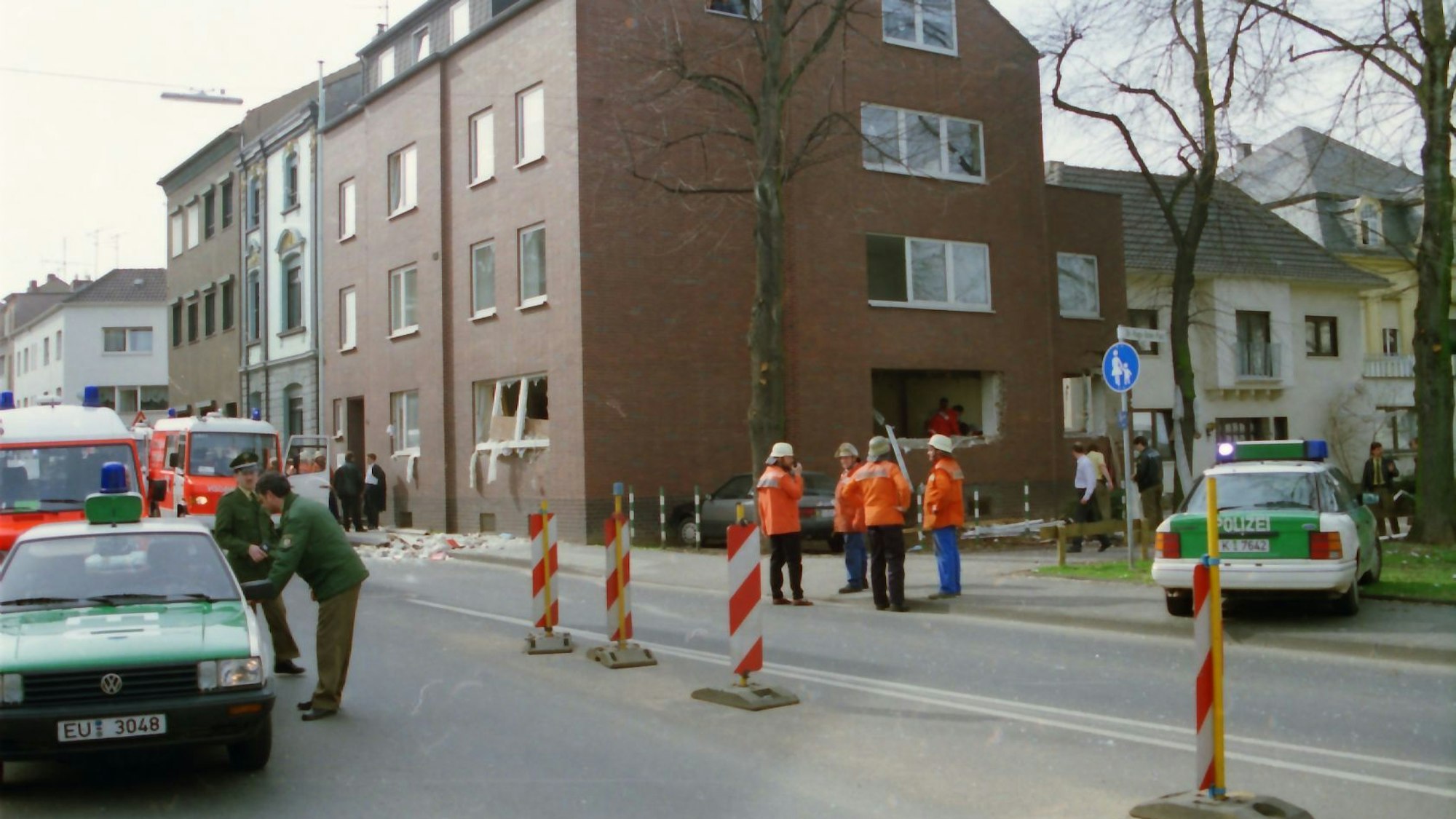 Das Bild zeigt im Hintergrund das Loch in der Fassade, das die Detonation verursacht hatte. Im Vordergrund sind zahlreiche Einsatzkräfte zu sehen.