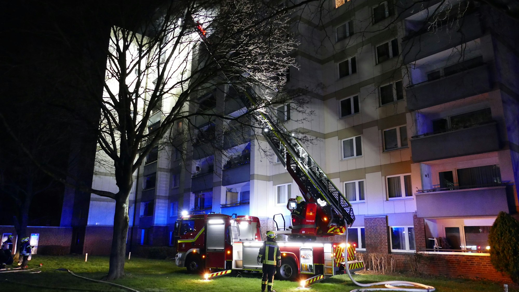Eine Drehleiter der Feuerwehr steht vor einem Hochhaus.