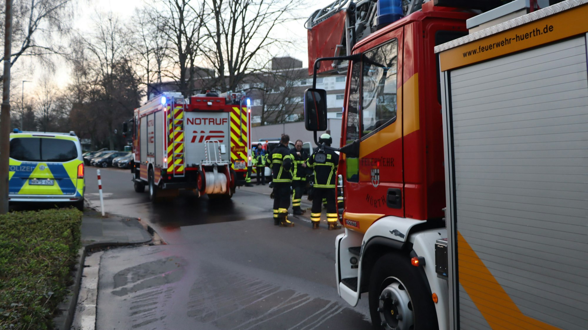 Feuerwehrleute stehen neben Feuerwehrautos.