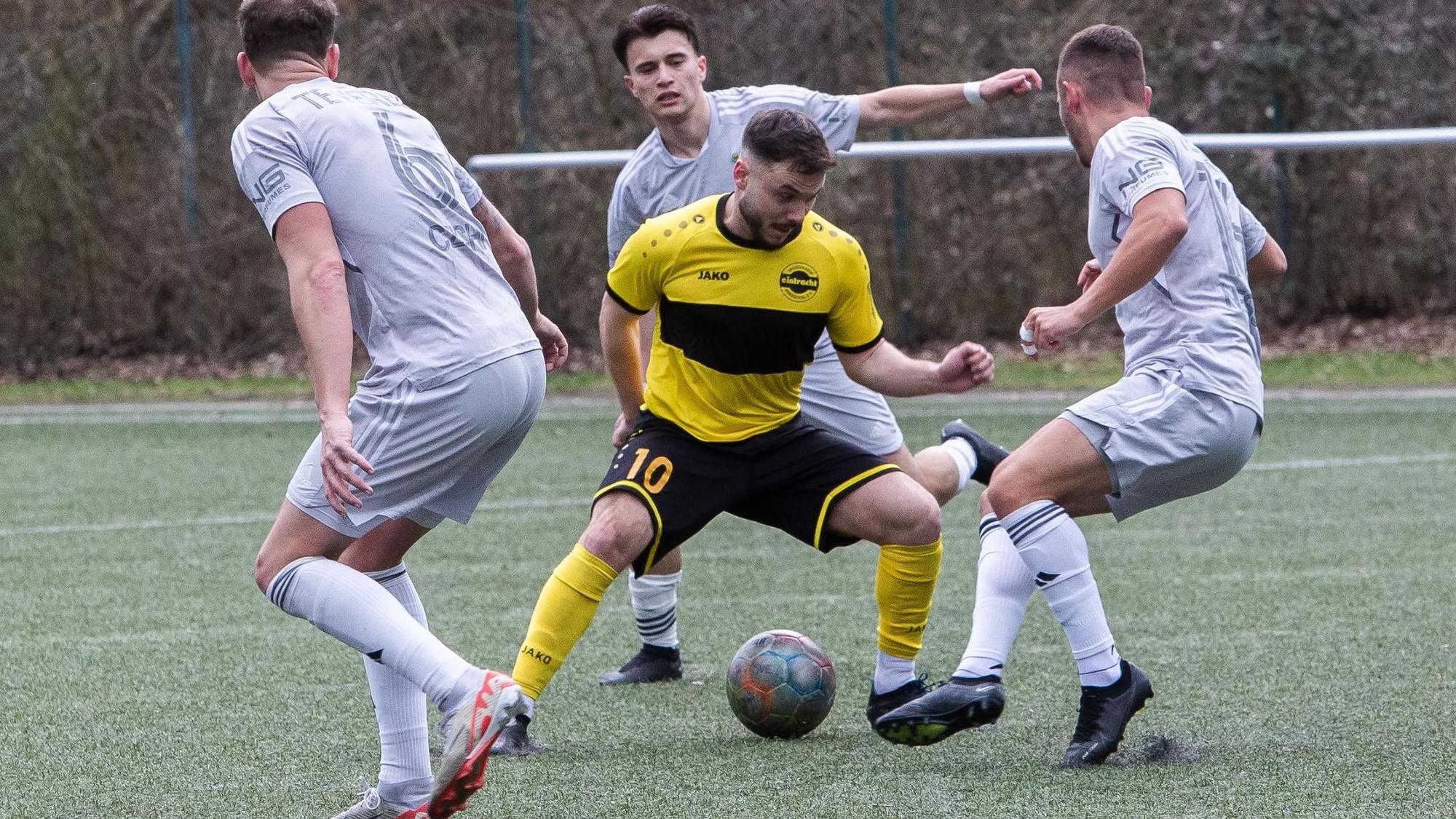 Ein Hohkeppeler Spieler wird mit dem Ball am Fuß von drei Spielern von Germania Teveren umringt.