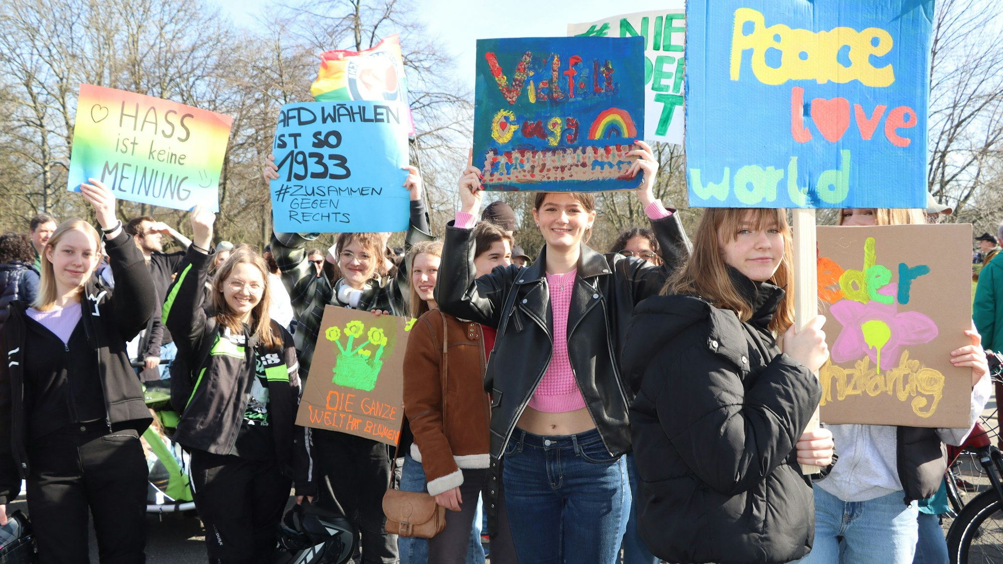 Junge Demonstrationsteilnehmer mit bunt bemalten Pappschildern.