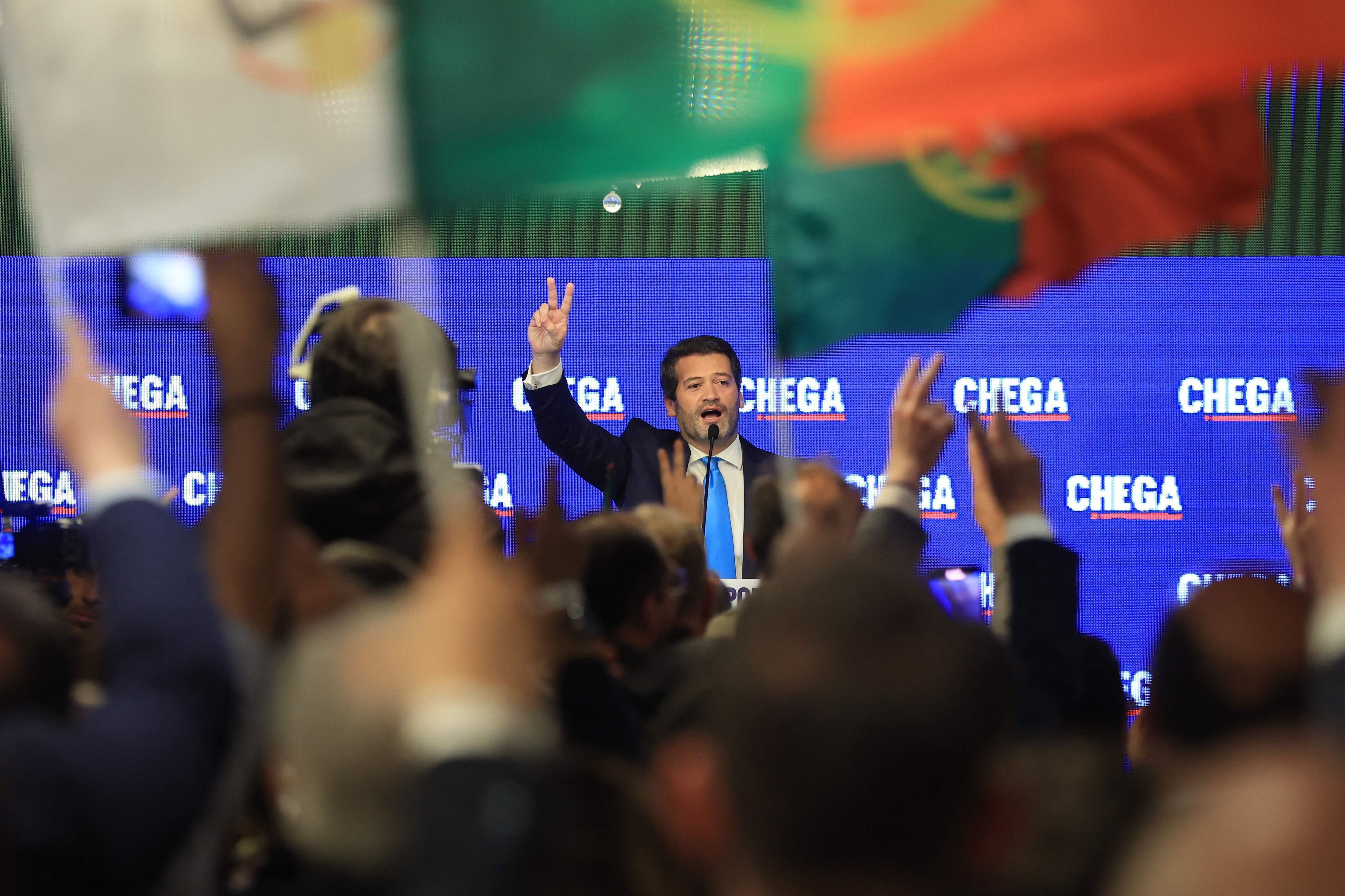 André Ventura, Chega-Vorsitzender, formt zwei Finger zu einem Siegeszeichen auf der Bühne vor Anhängern seiner Partei.