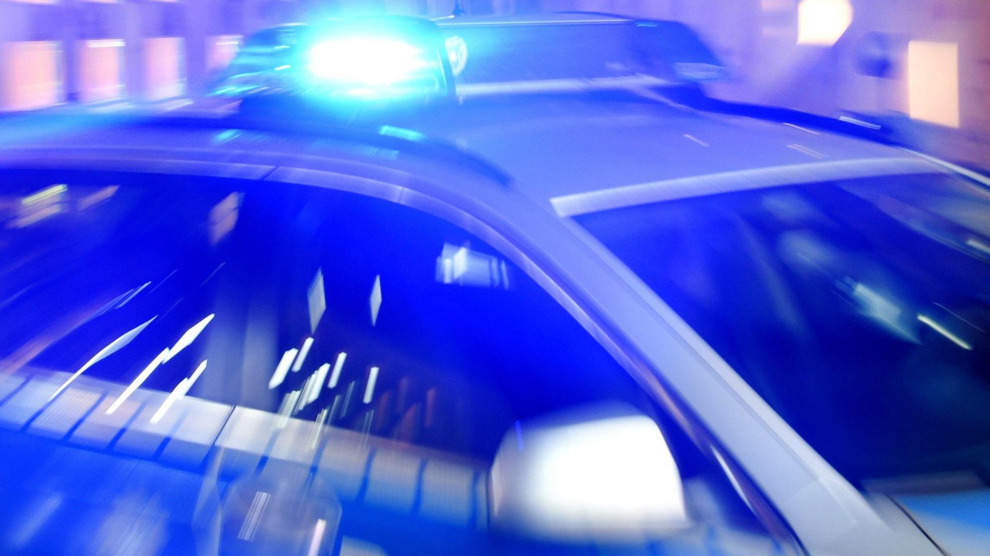Ein Streifenwagen der Polizei steht mit eingeschaltetem Blaulicht auf der Straße