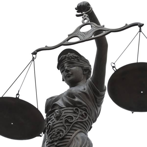 Eine Statue der Justitia mit einer Waage in ihrer Hand.