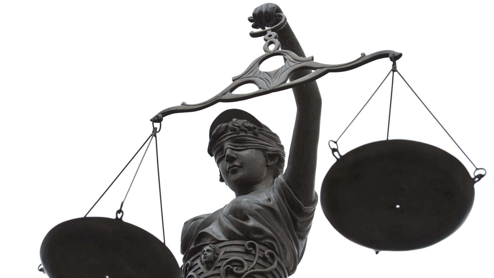 Eine Statue der Justitia mit einer Waage in ihrer Hand