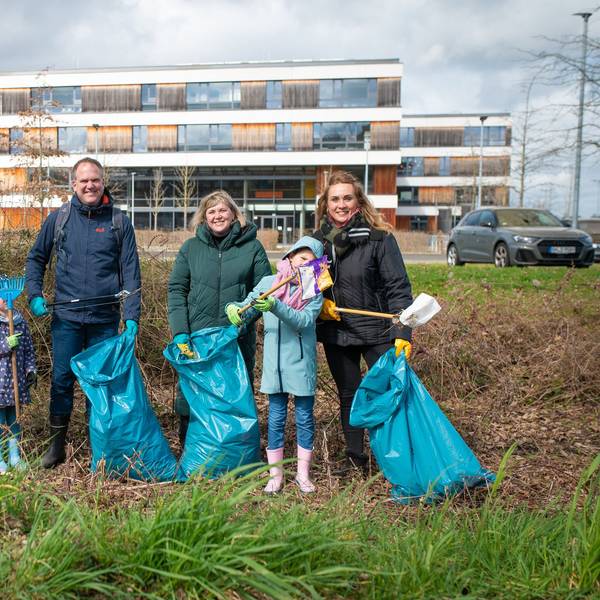 Männer, Frauen und Kinder mit Papiersammelzangen und blauen Müllsäcken hinter der Gesamtschule in Hermülheim.