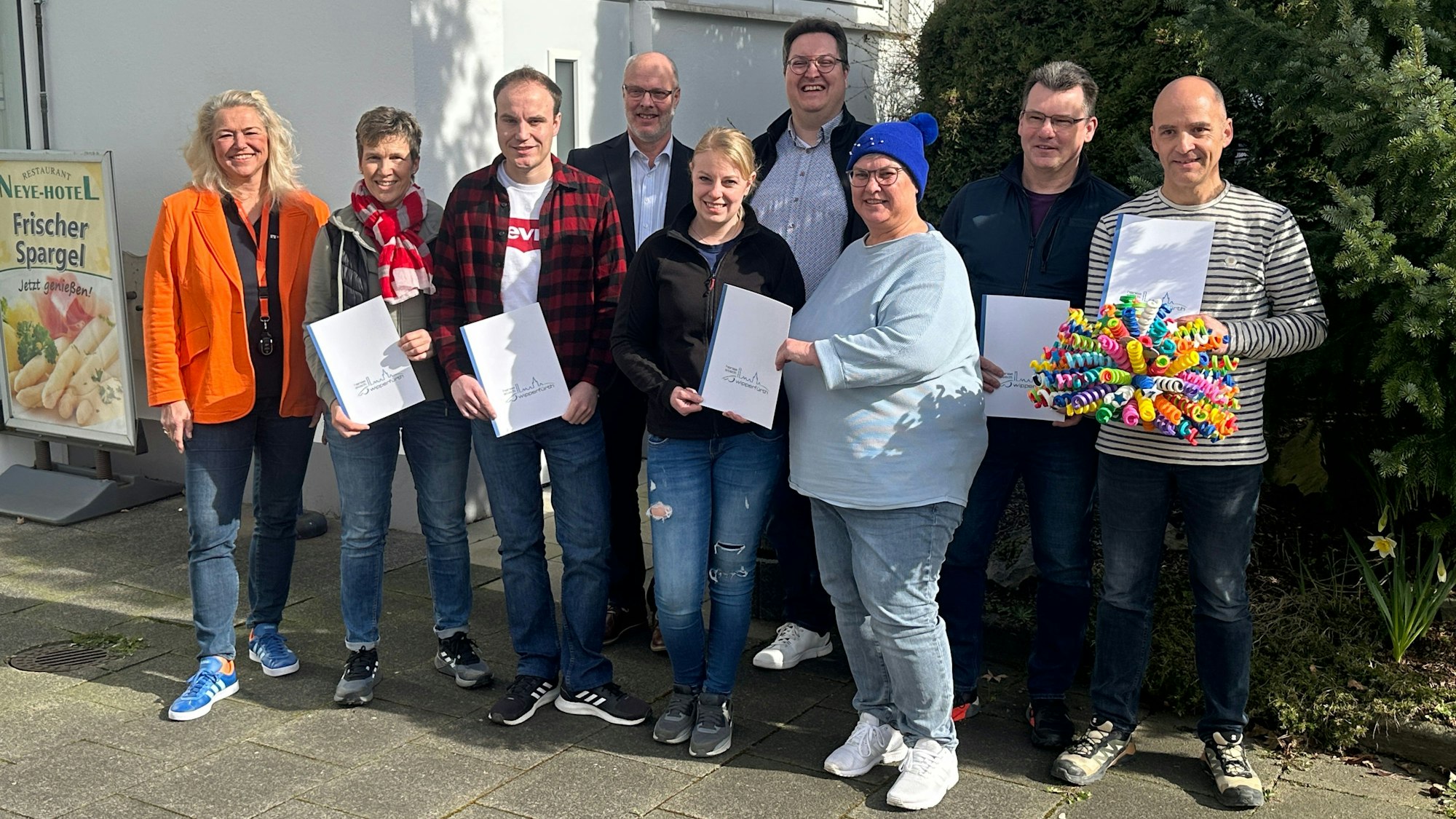 Eine Gruppe mit Urkunden in den Händen steht beisammen.