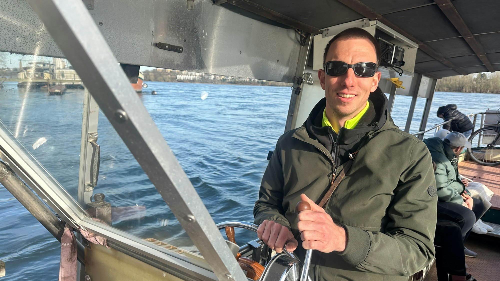 Ein junger Mann steht am Steuer eines Boots.