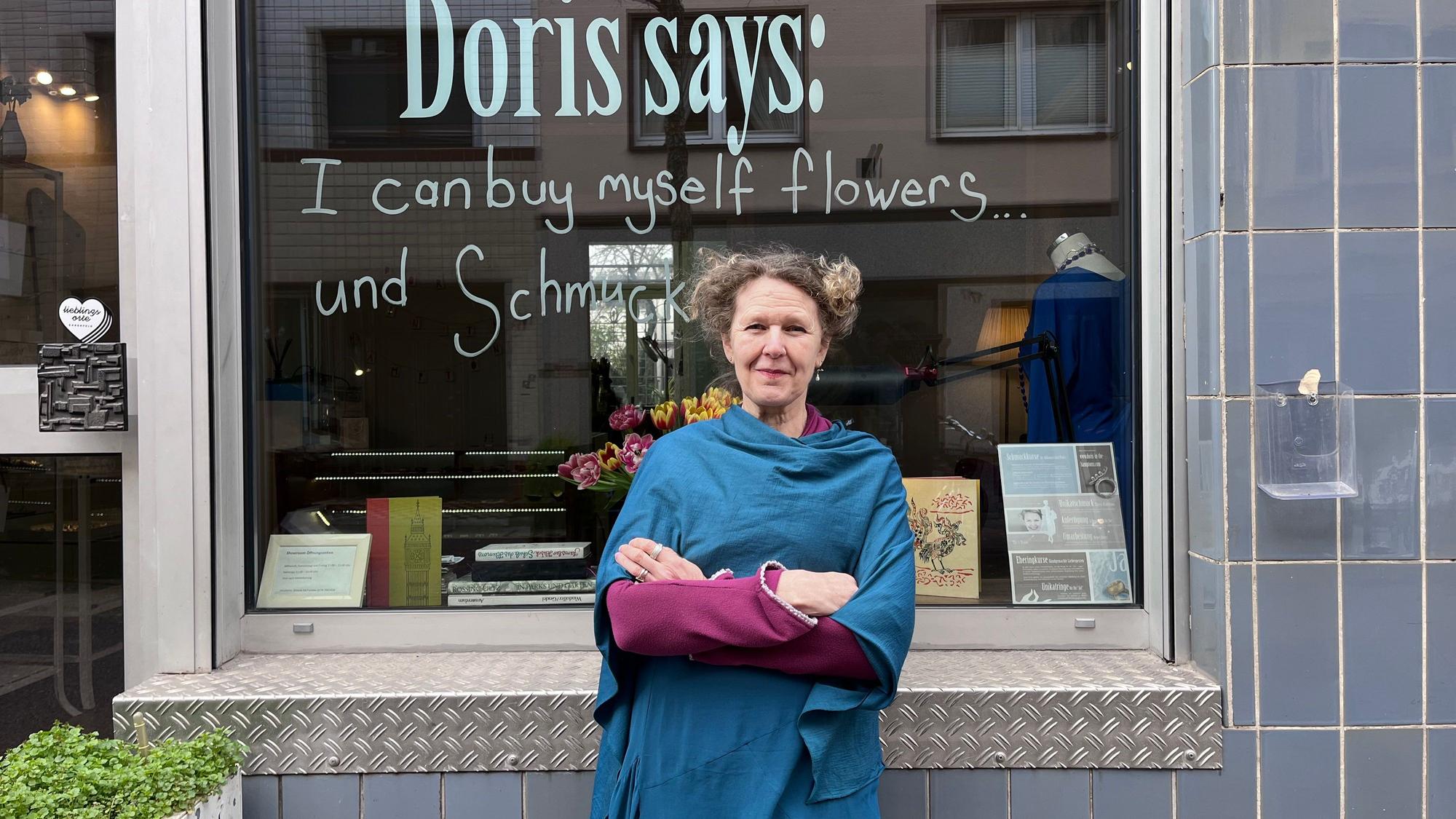 Eine Frau steht vor dem Schaufenster ihres Schmuckgeschäfts.
