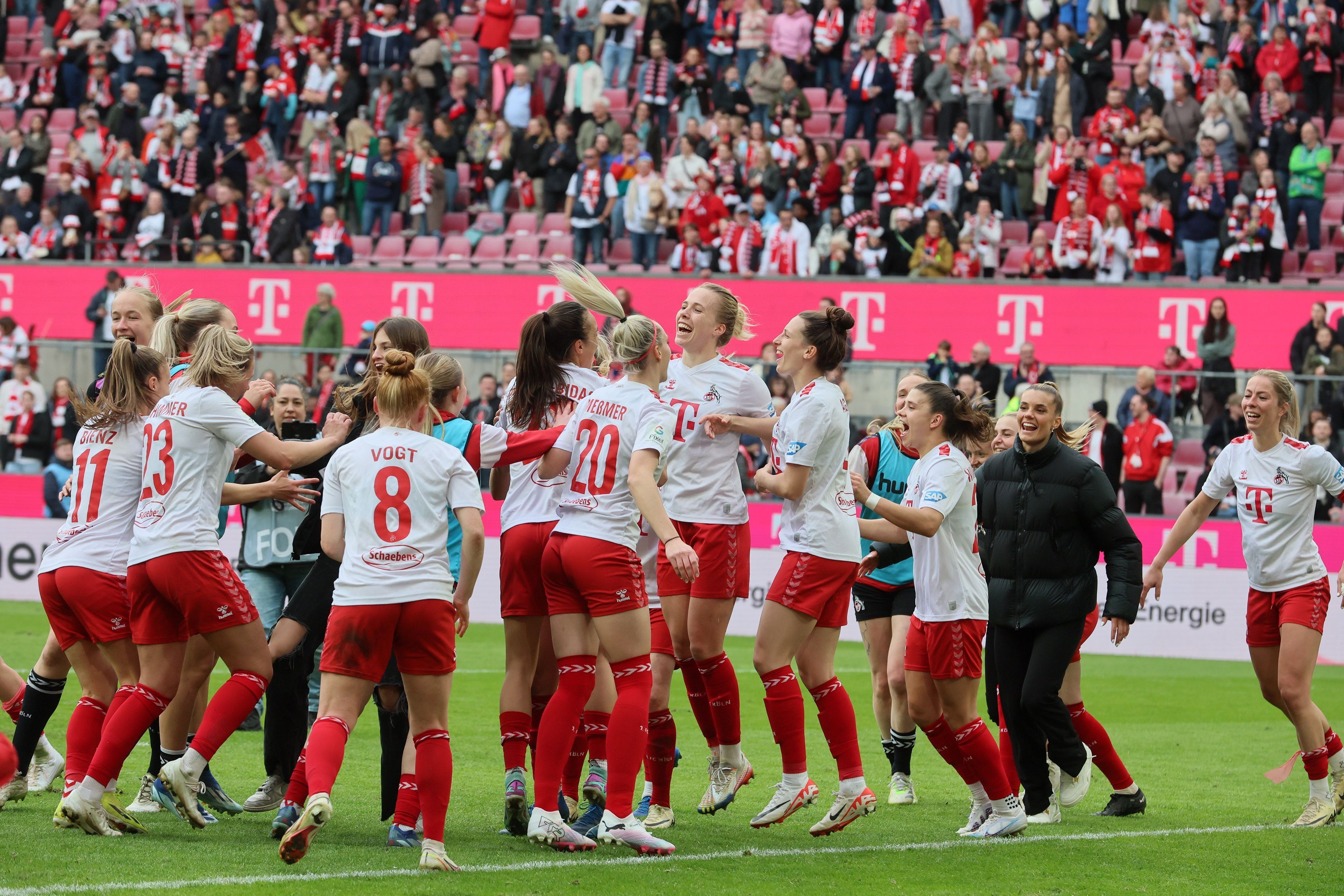 Fußballerinnen springen fröhlich auf dem Platz in die Luft.