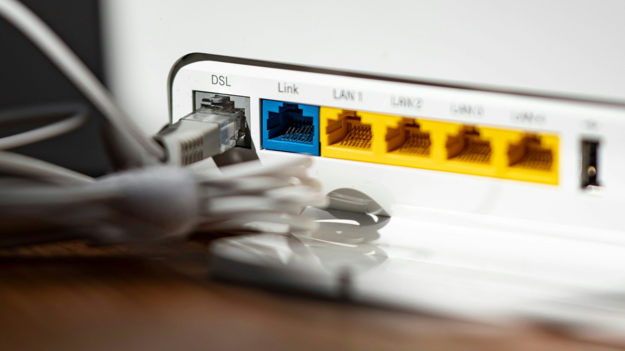 Ein LAN-Kabel steckt im DSL-Steckplatz eines WLAN-Routers. Die Bundesnetzagentur hat erstmals in Deutschland das „Recht auf schnelles Internet“ durchgesetzt. (Symbolbild)