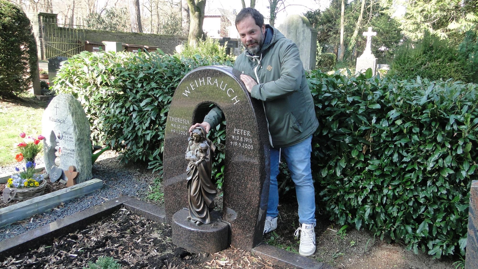 René Weihrauch demonstriert den Schaden an einer Marienstatue, deren Sockel aus dem Grabstein gebrochen wurde. Mit den Weihrauchs, die dort liegen, ist er nicht verwandt.