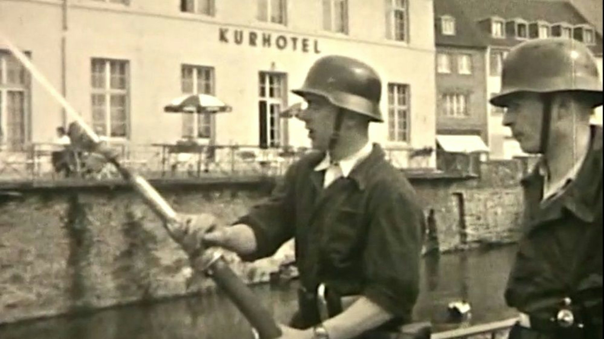Zwei Mitglieder der Gemünder Feuerwehr stehen mit einem Wasserschlauch vor dem Kurhotel.