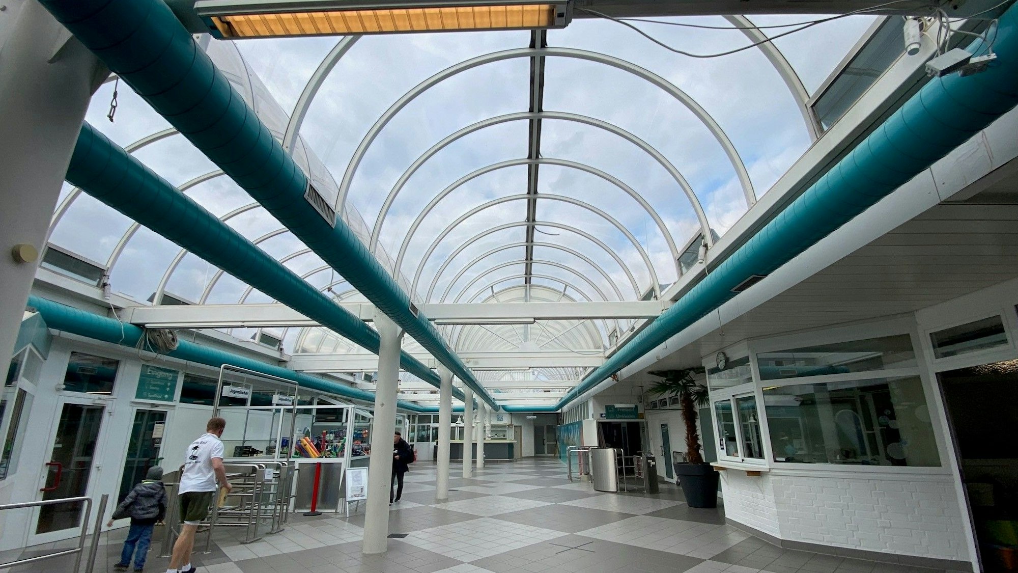 Zu sehe ist das gläserne Tonnendach eines Schwimmbads.