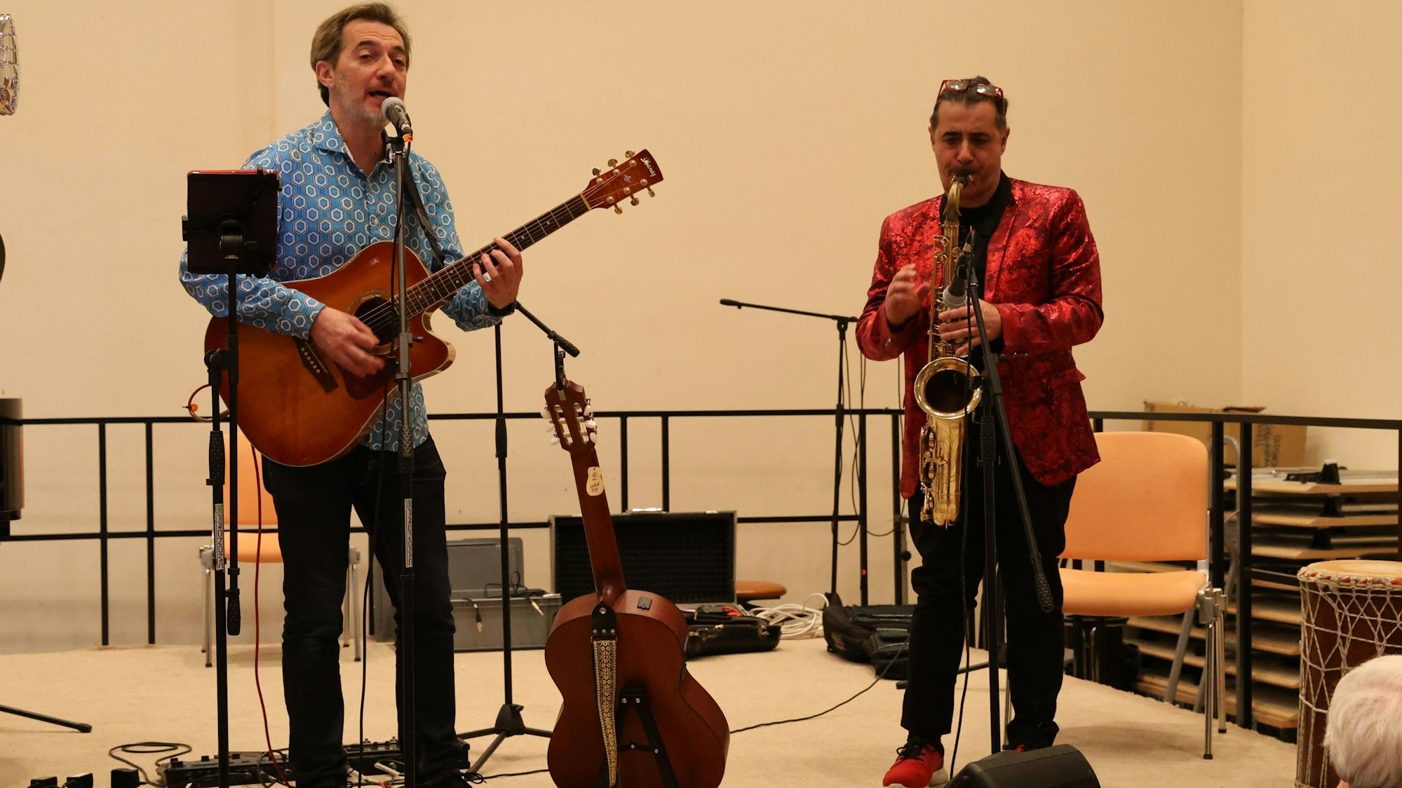 Zwei Männer spielen Gitarre und Saxophon.