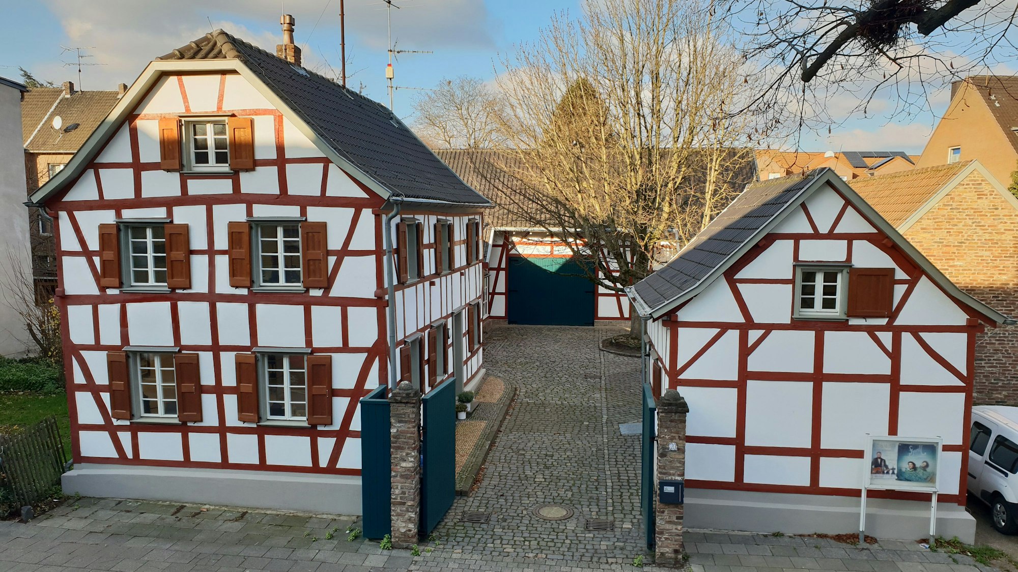 Zwei historische Fachwerkbauten einer Hofanlage mit großer Linde im Innenhof.