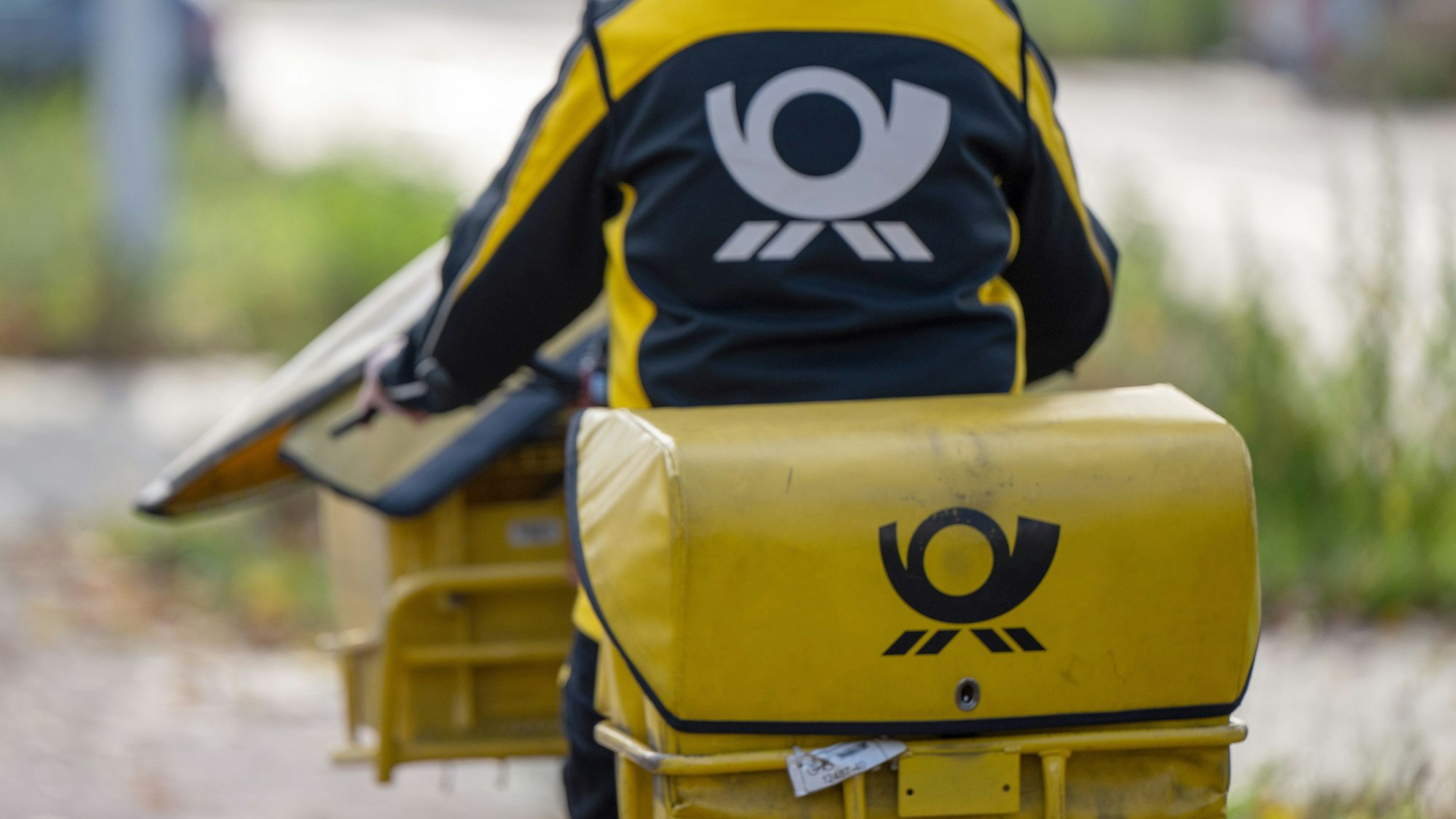 Eine Briefträgerin der Deutschen Post fährt auf ihrem Postfahrrad.