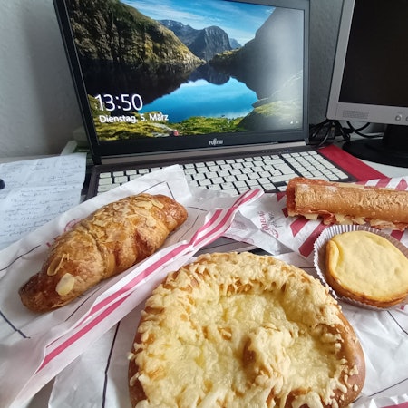 Backwaren liegen vor einem aufgeklappten Laptop