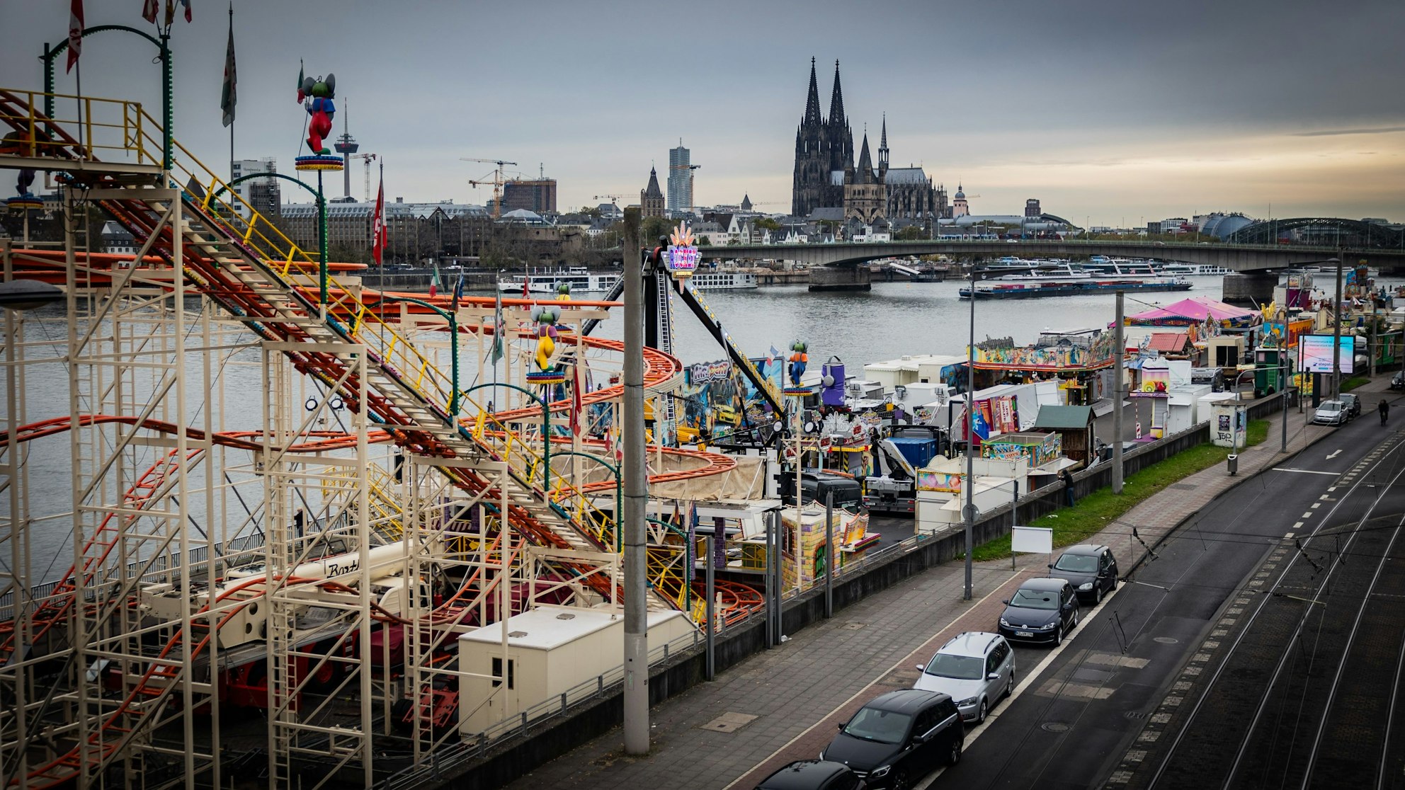 Fahrgeschäfte der Kirmes stehen am Rhein, mit Blick auf den Dom.