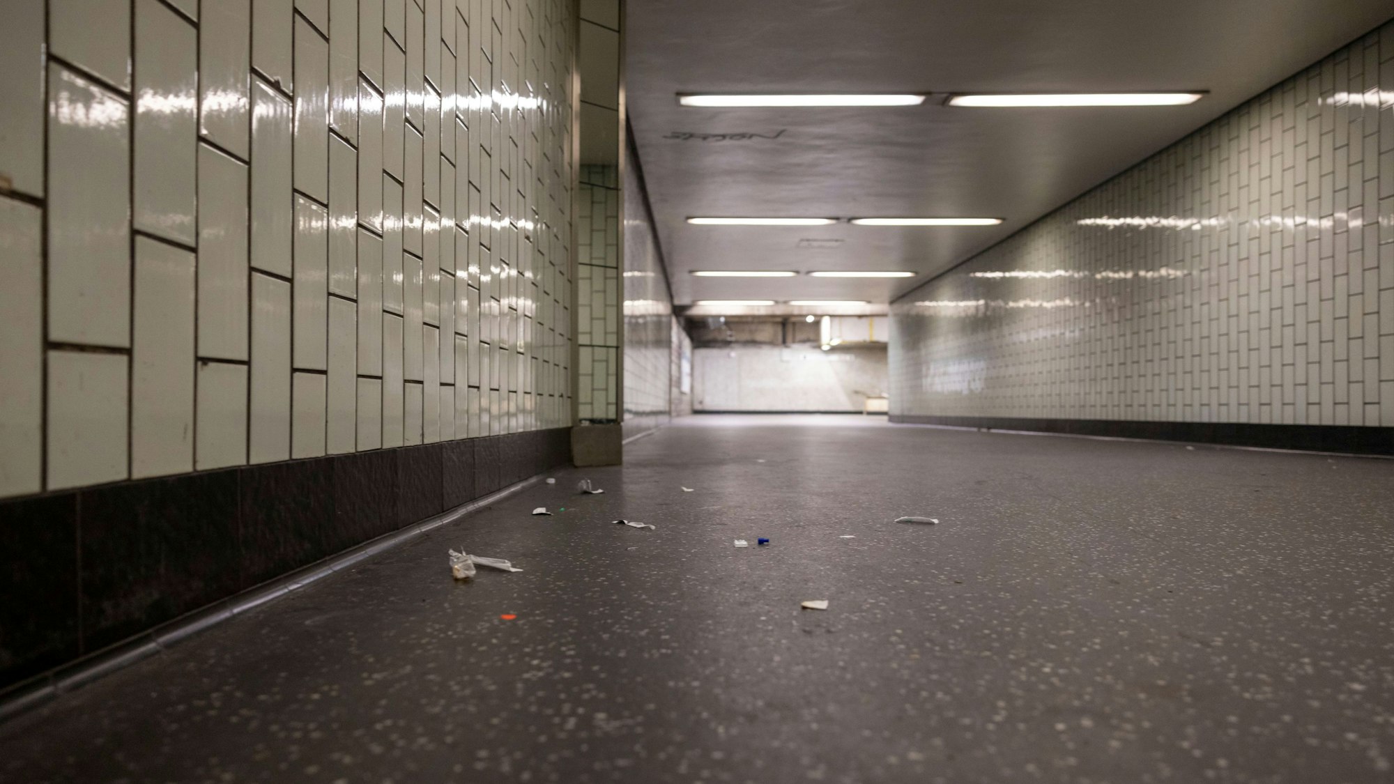 In einem Gang, der zum Bahnsteig führt, liegt Müll auf dem Boden.