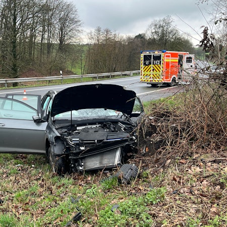 Ein zerstörtes Auto steht neben einer Straße.