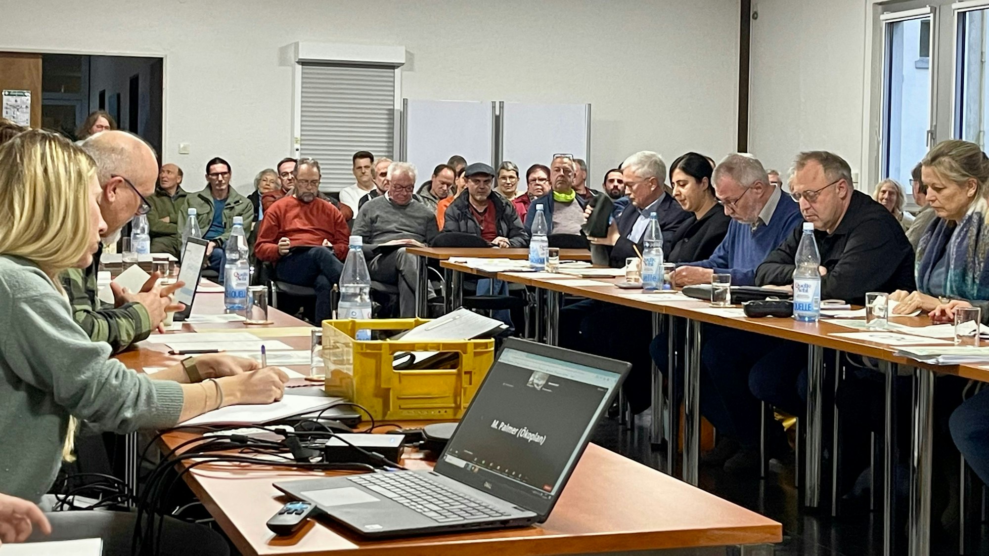 Männer und Frauen sitzen an langen Tischen.