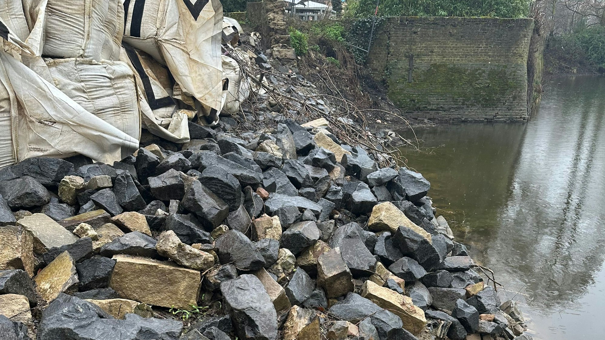 Steine der Ufermauer an der Groov in Zündorf liegen auf einem Haufen. Sie wird neu aufgebaut.