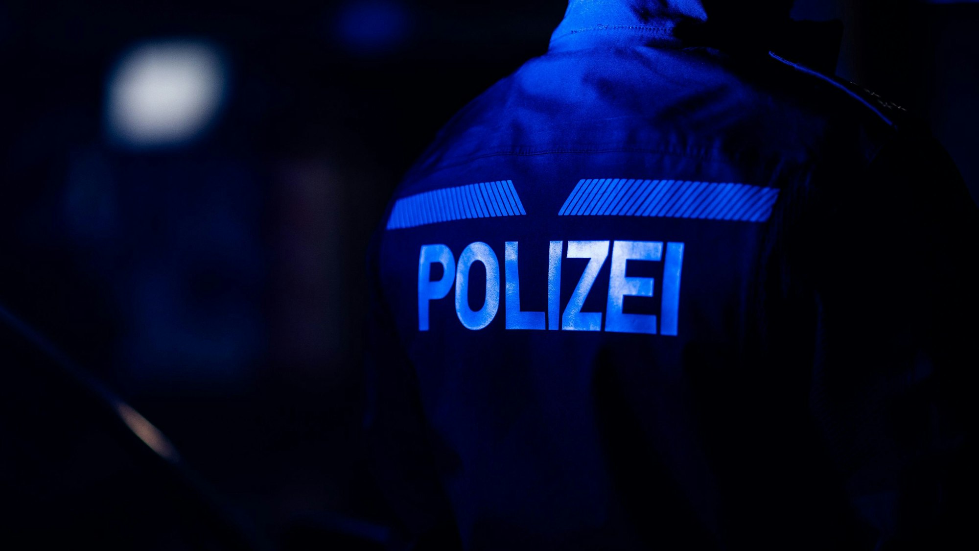 Ein Polizist steht neben einem Polizeiauto.