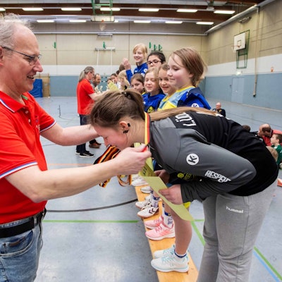 Ein Mann hängt einem Mädchen eine Medaille um.