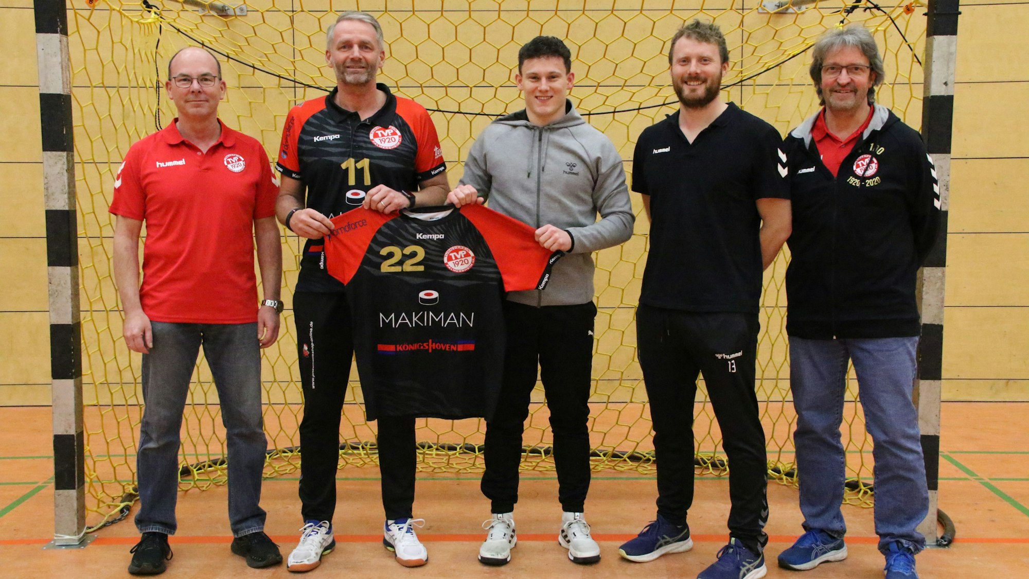 Trainer Peter Trimborn und Marius Schmitz halten das Trikot mit der Nr. 22 hoch. Daneben stehen die beiden Vorsitzenden und René Lönenbach.
