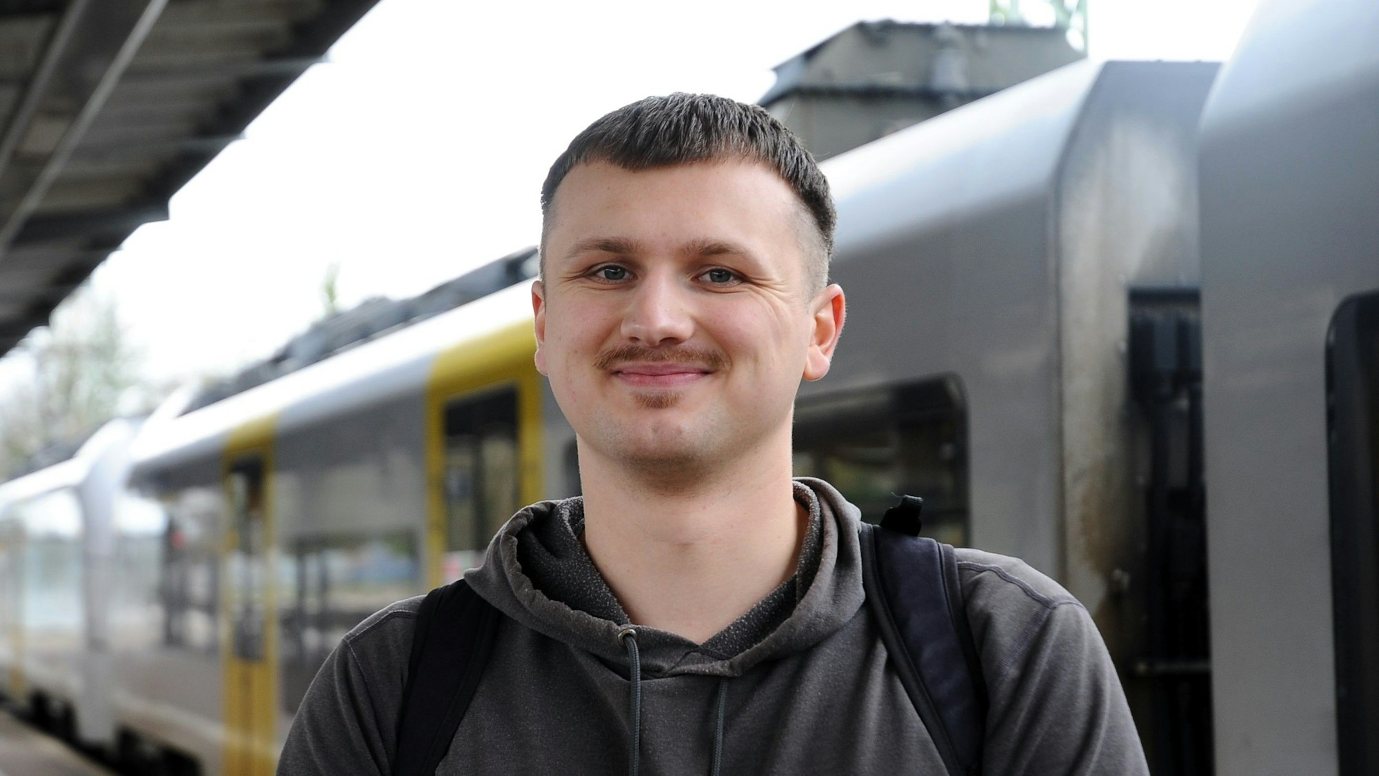 Zu sehen ist ein Mann vor einem Zug.