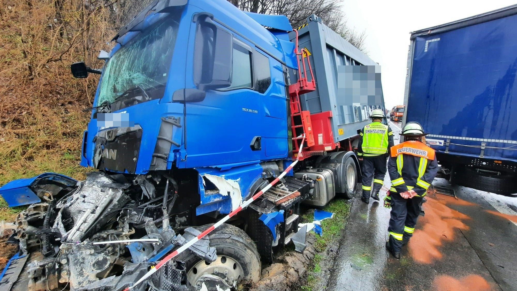 Ein blauer Lkw liegt halb im Graben, der Motor ist herausgerissen. Feuerwehrleute laufen über die Fahrbahn.