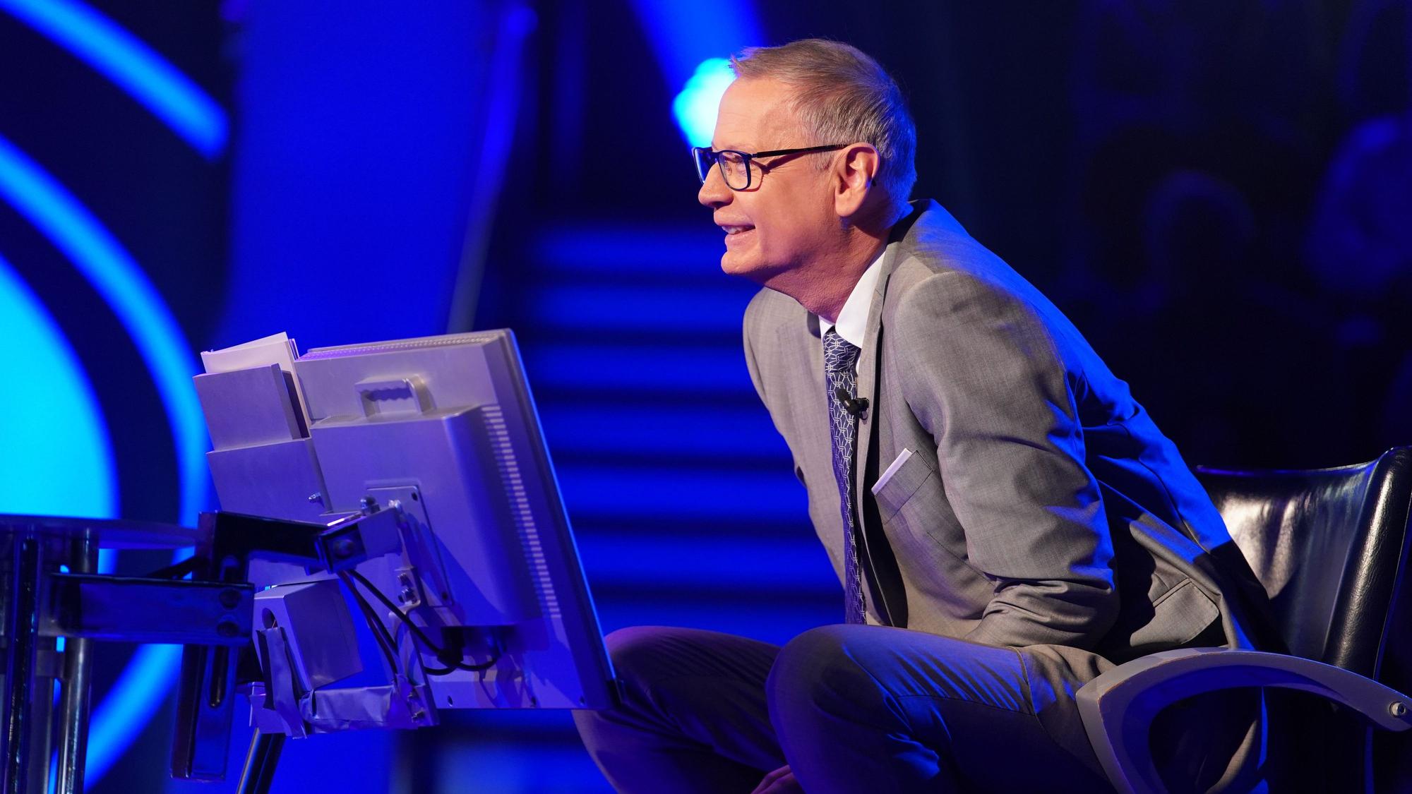 „Wer wird Millionär?“-Moderator Günther Jauch sitzt am Pult der RTL-Quizshow und blickt lächelnd zu einem Kandidaten herüber.