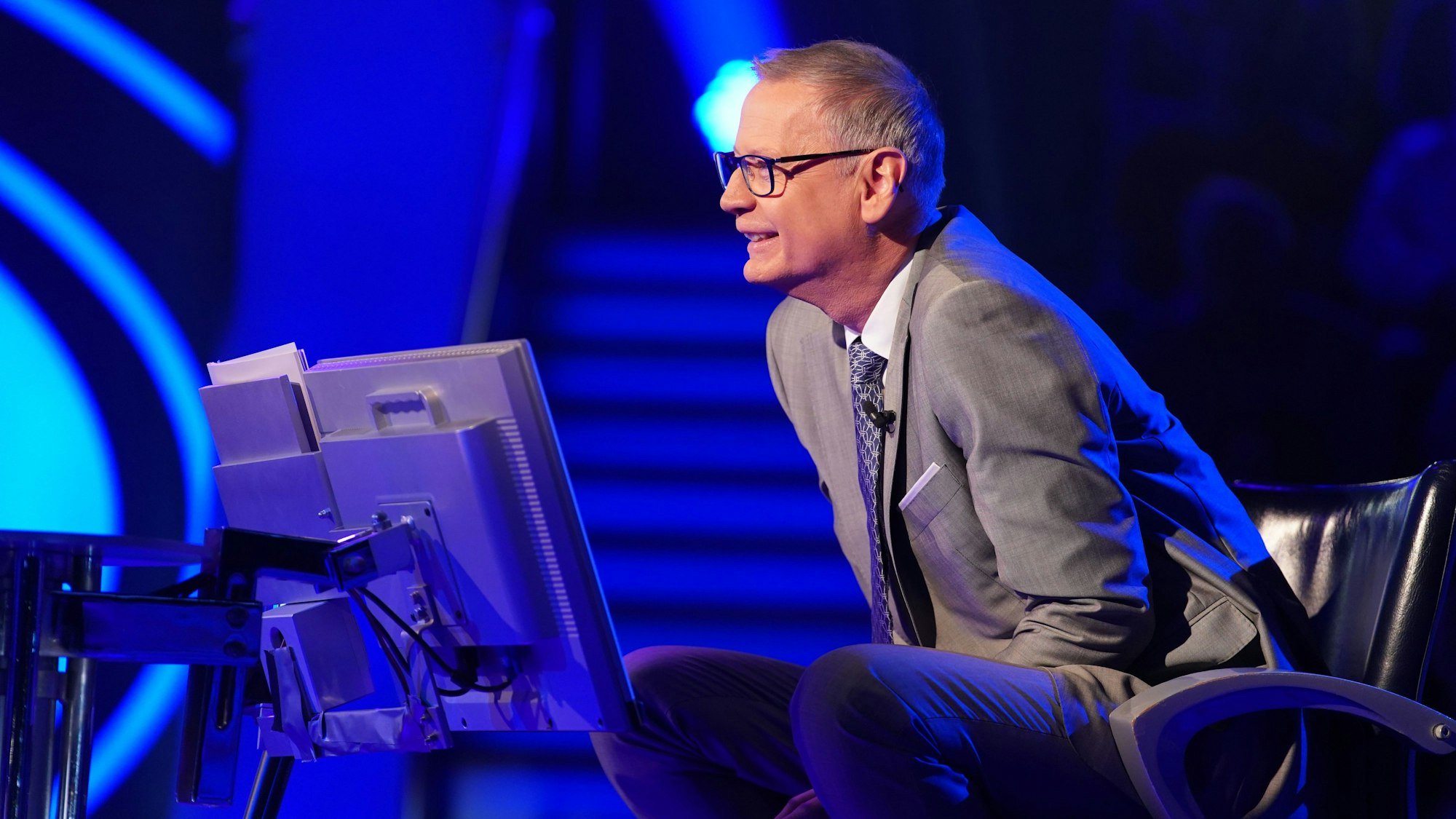 „Wer wird Millionär?“-Moderator Günther Jauch sitzt am Pult der RTL-Quizshow und blickt lächelnd zu einem Kandidaten herüber.