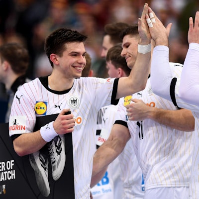 Ein grinsender Mann schlägt in die Hand einer Person außerhalb des Bildausschnittes ein.