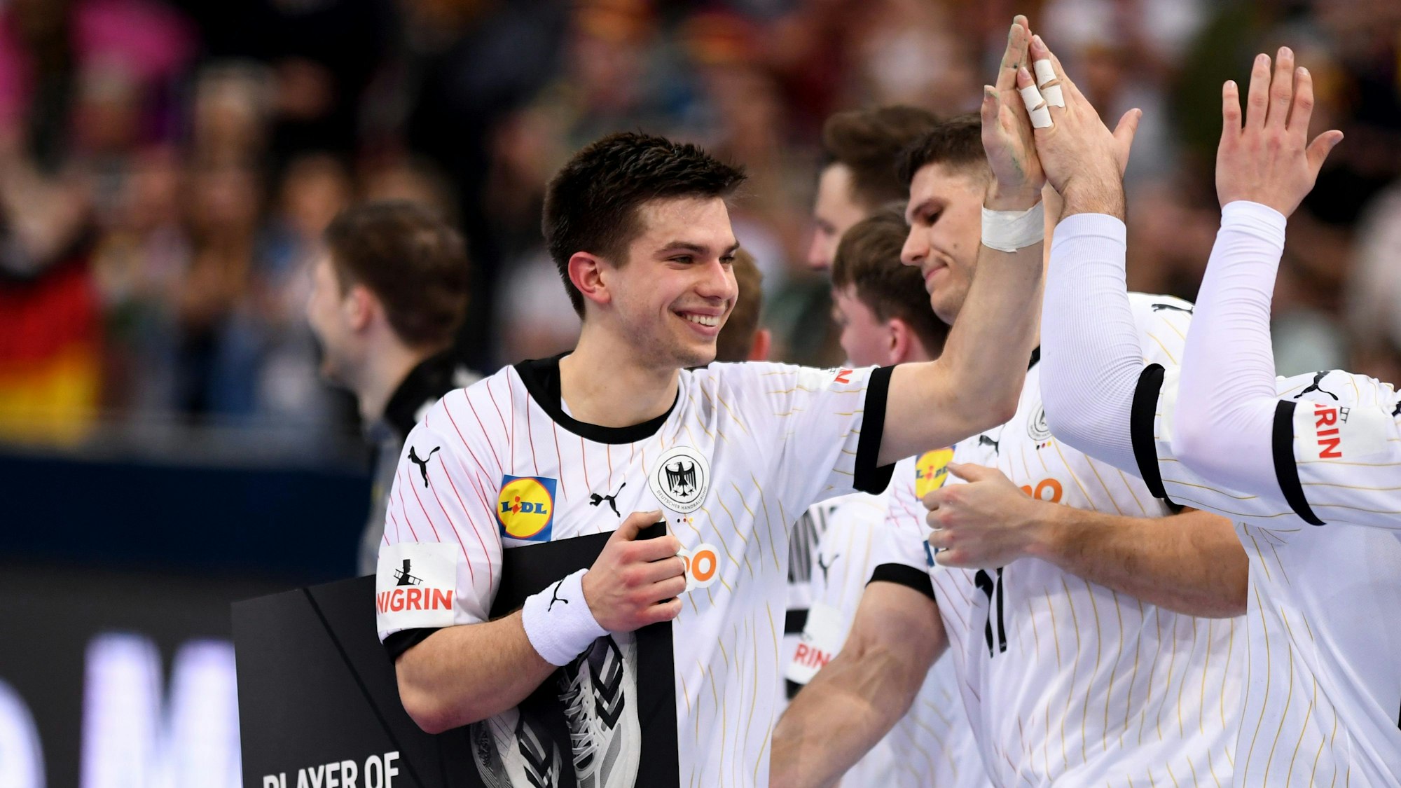 Ein grinsender Mann schlägt in die Hand einer Person außerhalb des Bildausschnittes ein.