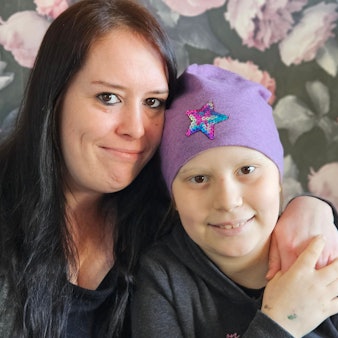 Ein Mädchen mit Kopfbedeckung und mit ihrer Mutter.