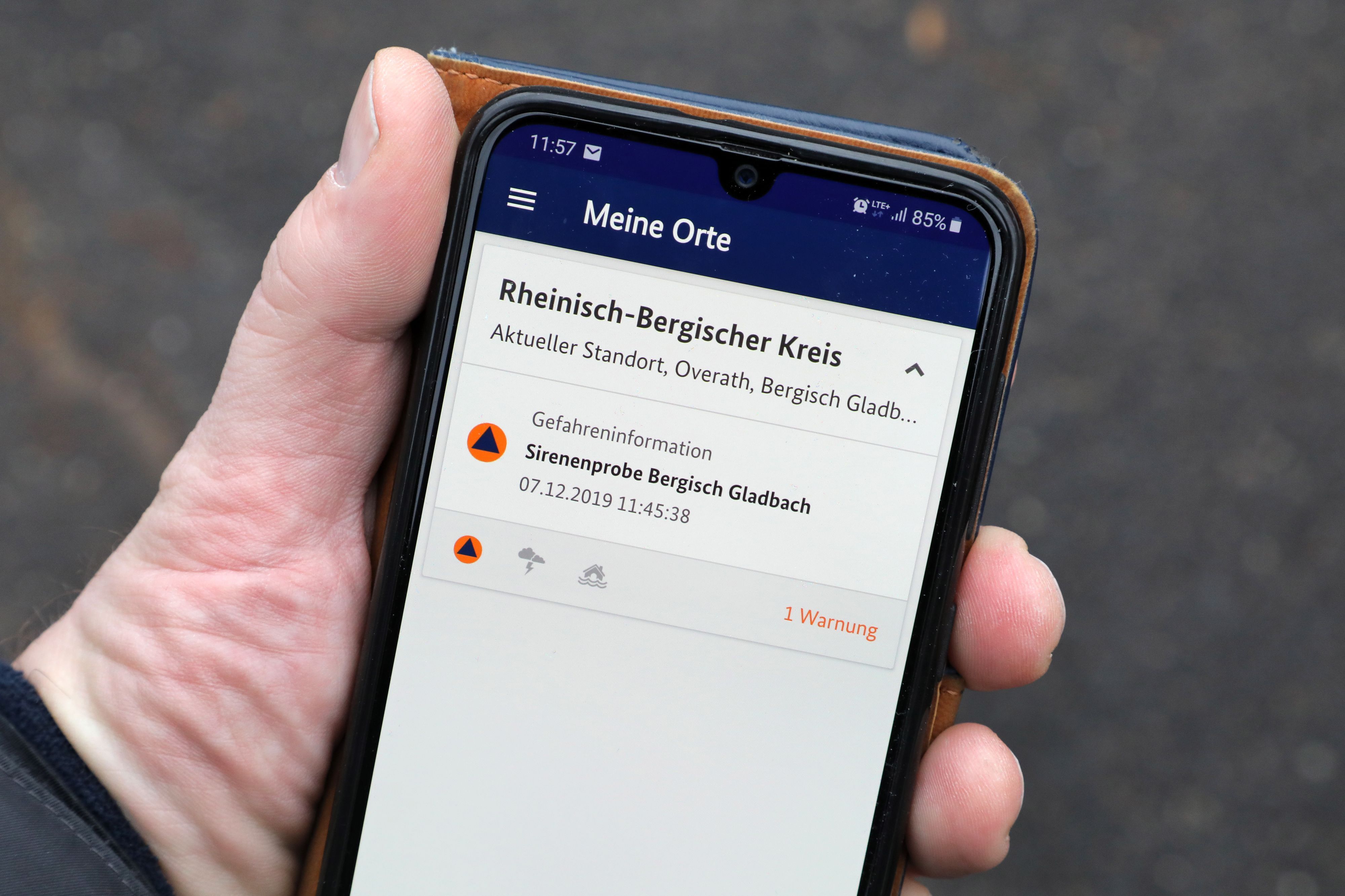 Eine Hand hält ein Smartphone mit einer Siorenenproben-Meldung.