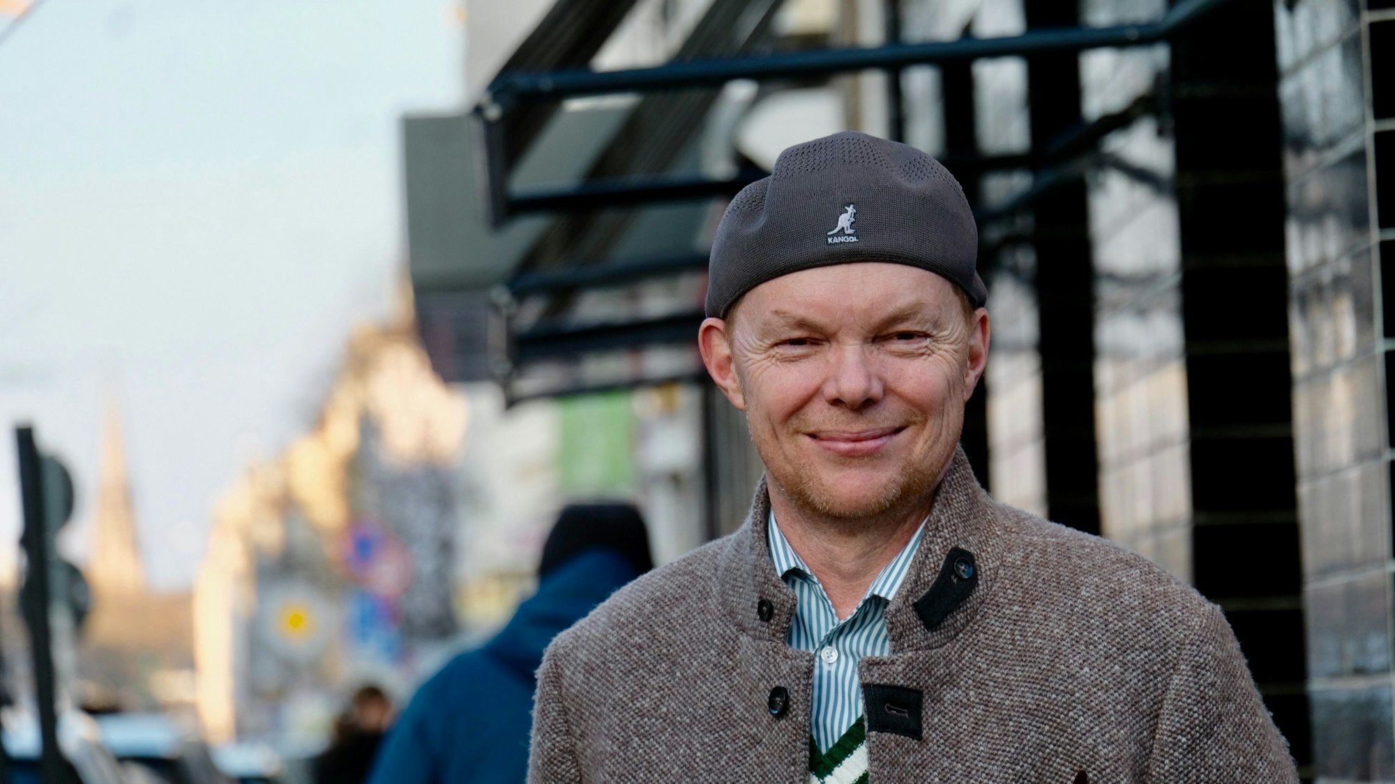 Ein Mann mit umgedrehter Kappe auf dem Kopf steht auf einer belebten Straße.