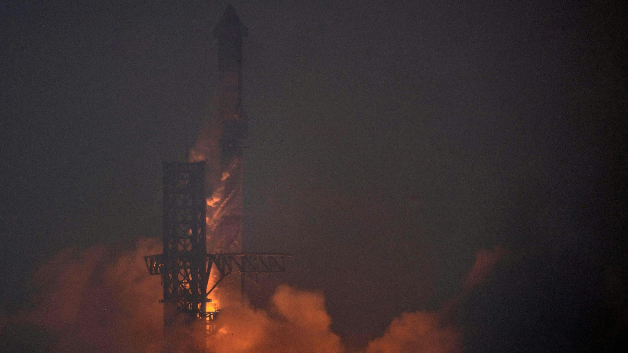 Im Dunkeln findet ein Raketenstart statt, dessen Antrieb die entstehende Rauchentwicklung beleuchtet.