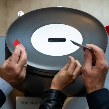 Abgeordnete werfen im Bundestag ihre Stimmkarte in der namentlichen Abstimmung ein.