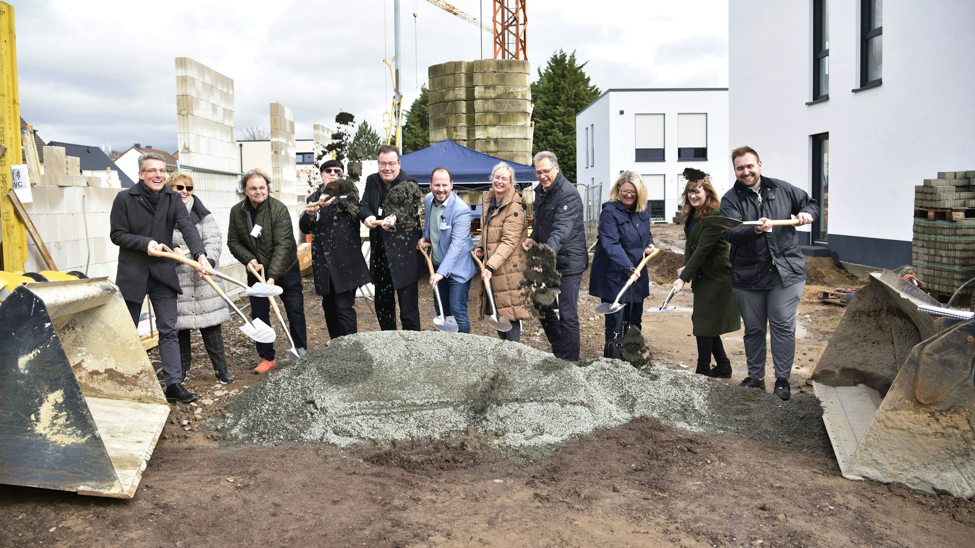 Mehrere Menschen stehen auf einer Baustelle und haben Spaten in der Hand.