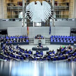 Die Abgeordneten des Bundestags stimmen über die Lieferungen von Taurus-Marschflugkörpern an die Ukraine ab. Mehrere Abgeordnete sitzen auf den blauen Sitzen im Plenum des Bundestags.