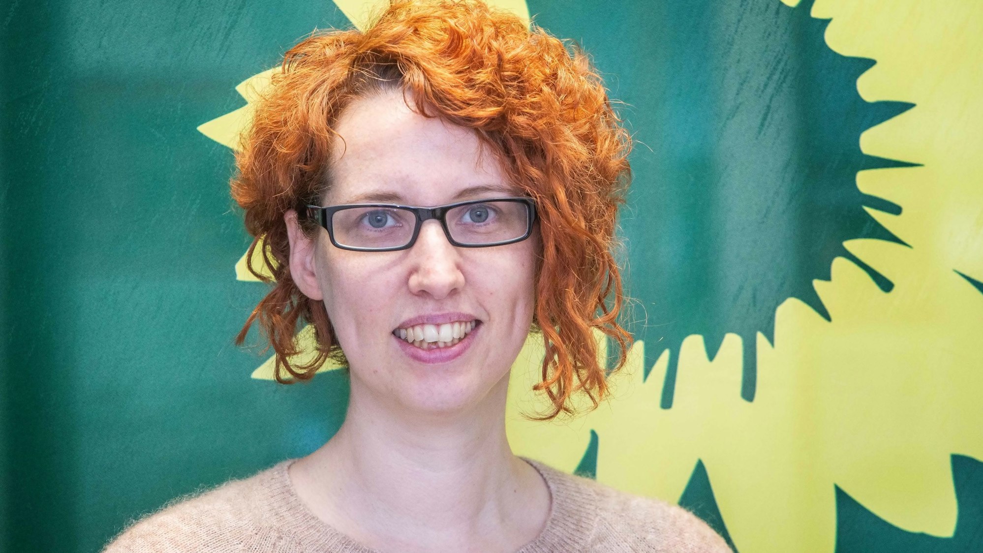 Porträt einer Frau vor dem Symbol der Grünen.