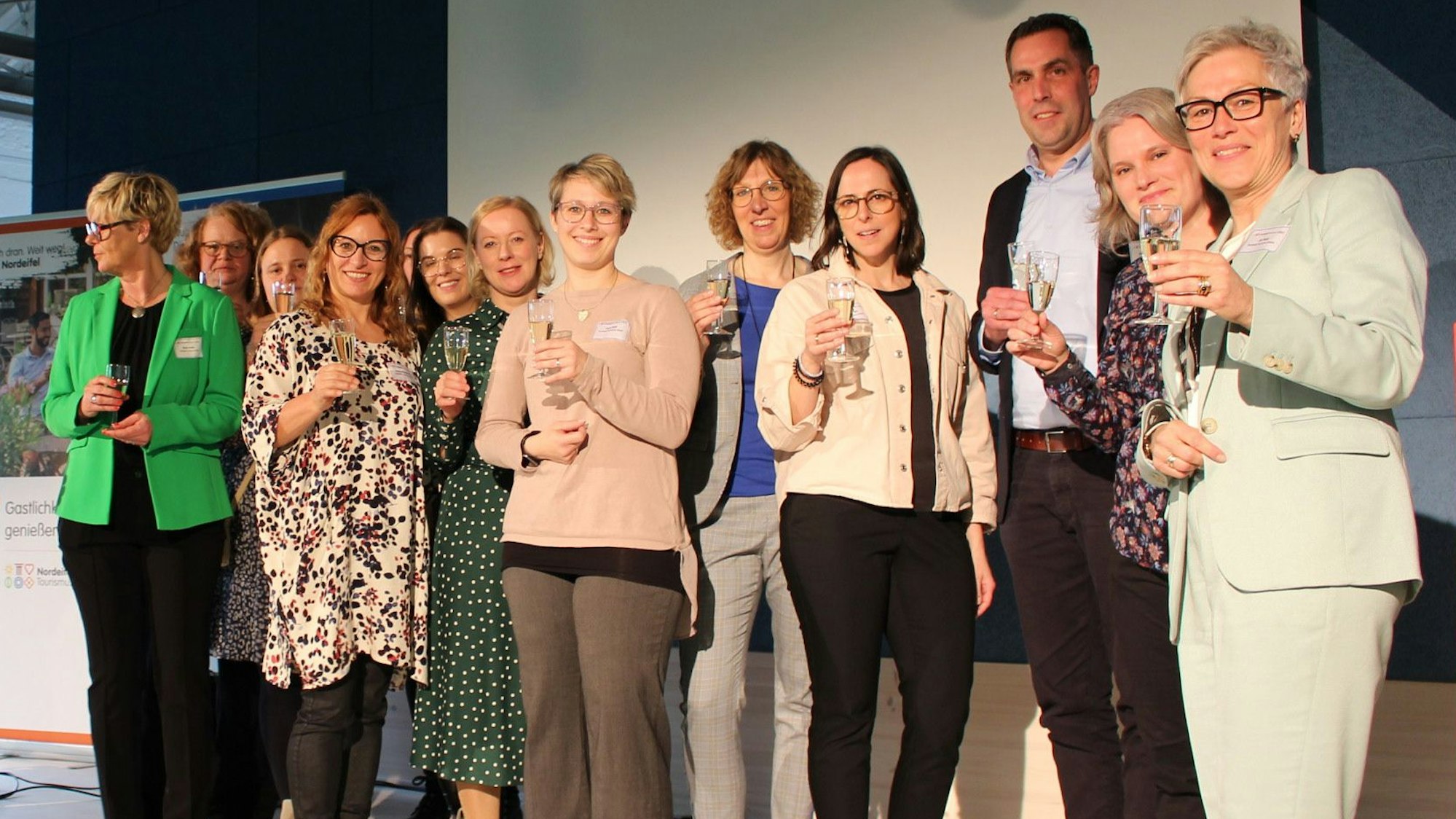 Das Team der Nordeifel Tourismus steht auf der Bühne und prostet den Gästen zu.